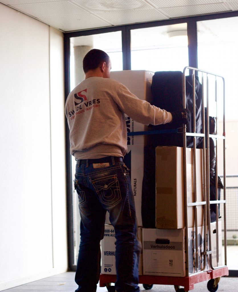 SW de Vries rolt een kar met spullen naar binnen.